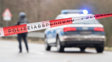Polizeibeamte stehen an einer Absperrung an der Kreisstraße 22, rund einen Kilometer von dem Tatort entfernt, an dem zwei Polizeibeamte durch Schüsse getötet wurden.