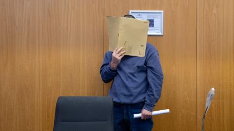 Im Landgericht Ulm hält sich ein Mann eine Akte vor das Gesicht.