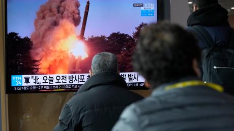 Menschen sehen sich im Bahnhof von Seoul eine Nachrichtensendung an, in der ein Bild eines Rakenstarts in Nordkorea gezeigt wird.