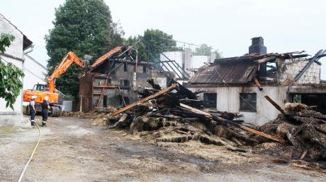 Die Aufräumarbeiten haben in Hollenbach am abgebrannten Stadel begonnen. Aber immer wieder flackern in den Trümmern Flammen auf.