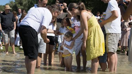 Pfarrer Christian Agnethler (links) tauft die kleine Sophia im Kreis ihrer Familie mit Wasser aus einer Muschel „Im Namen des Vaters, des Sohnes und des Heiligen Geistes“.
