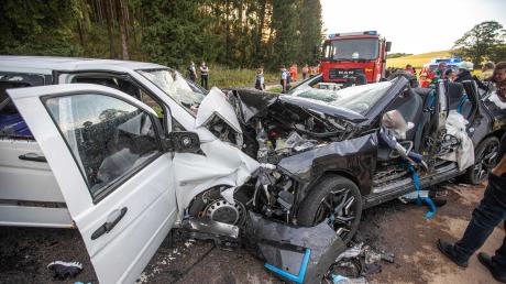 Rettungskräfte stehen an den zerstörten Fahrzeugen. Beim schweren Unfall auf der B28 bei Römerstein ist ein Mensch ums Leben gekommen, weitere neun wurden schwer verletzt. 