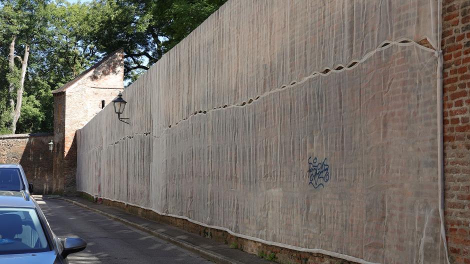 An der Stadtmauer im Schwedenweg gibt es Schäden. Die Mauer bröckelt. Ein Netz ist zur Sicherung von Passanten angebracht  