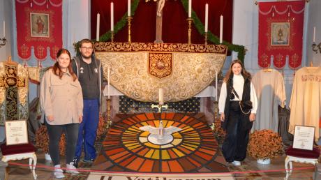 Stolz stehen Theresa Lindenmaier, Johannes Lohner und Magdalena Hauf in der Stadtpfarrkirche Gundelfingen neben ihrem Körnerbild, das sie passend zum 60. Jubiläum des Zweiten Vatikanum für das Erntedankfest gestaltet haben.