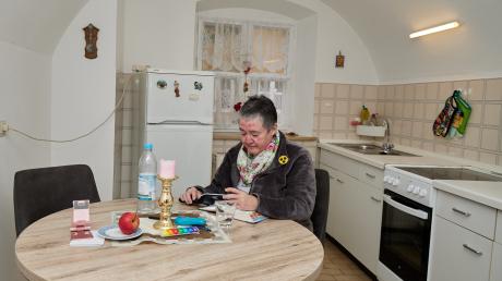 Johanna Grünwald liest in der Küche mit einer Lupe in der Bibel. Im Winter will sie aufgrund der steigenden Energiekosten nur noch einen Raum in ihrer Augsburger Fuggerei-Wohnung heizen.