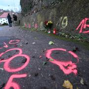 Blumen und Kerzen stehen an Markierungen der Spurensicherung der Polizei an einem Tatort auf einem Weg in Illerkirchberg. Zwei Mädchen wurden angegriffen, eine von ihnen starb.