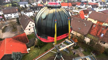 Die tonnenschwere Kuppel der Biburger Kirche wird mit einem Kran nach unten befördert.