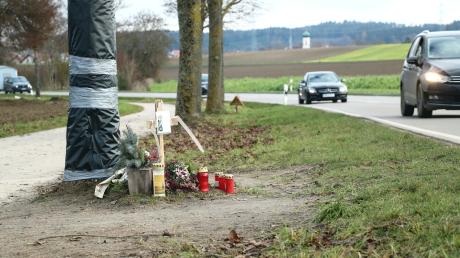 Blumen, Kreuz und Kerzen erinnern an den Unfalltod eines 27-Jährigen zwischen Haunswies und Affing. Für Schäden am Baum bekommt der Landkreis Geld von der Versicherung.