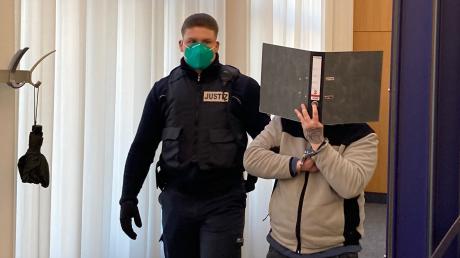 Am Landgericht Ulm hat der Prozess um den gewaltsamen Tod eines 31-Jährigen in einer WG in Laichingen begonnen. Hier wird einer der beiden Angeklagten gefesselt in den Sitzungssaal geführt. 