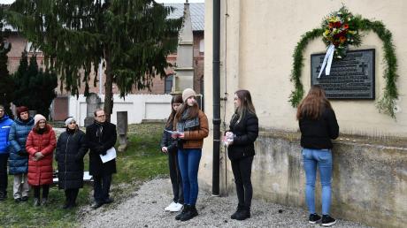 Schülerinnen des Albertus-Gymnasiums zünden unter der Gedenktafel an der Johanneskirche zwölf Kerzen an. 
