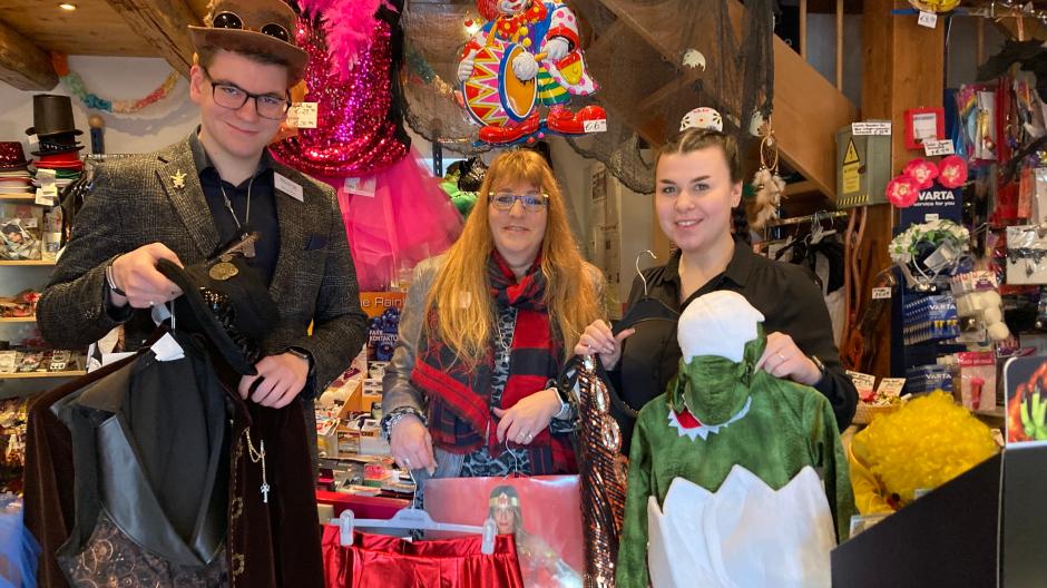 Vincent Nusser mit "Steampunk"-Hut, Chefin Claudia Nusser und Auszubildende Jennifer Klossek mit dem beliebten Dinobaby-Anzug zeigen die neuesten Faschingstrends dieser Saison.