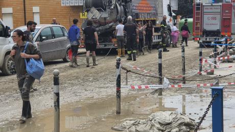 Menschen und Helfer sind auf einer Straße zu sehen, die überschwemmt wurde. Nach den dramatischen Überschwemmungen wegen heftiger Regenfälle in der italienischen Region Emilia-Romagna gibt es noch immer keine Entwarnung.