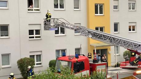 Eine Frau spricht in Königsbrunn mit einem Feuerwehrmann auf der Drehleiter. Drei Wohnungen mussten Einsatzkräfte öffnen, nachdem ein Longboard einen Brand ausgelöst hatte.