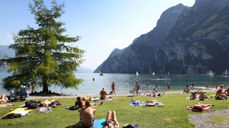 Touristen bräunen sich am Strand von Riva del Garda. 
