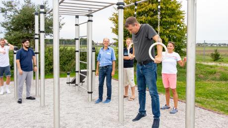 Gemeinderat Rüdiger Landto testet unter den Augen von Gemeinderatsmitgliedern und Vertretern der Jugendpflege Lechfeld an der neuen Calisthenics-Anlage sein Können an den Ringen.