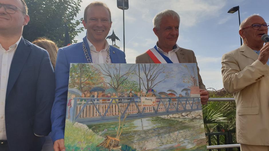 Ein besonderes Geschenk der Meringer Reisegruppe für Ambérieu war das von Harold Frkovic aus Mering in Acrylfarben gemalte Bild von der gemeinsamen Einweihung der neuen Brücke der Freundschaft in Mering am 1. Mai 2023.