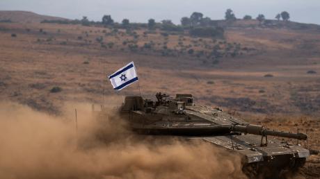 Ein Panzer mit einer israelischen Flagge auf dem Dach fährt zu einem Sammelplatz nahe der israelisch-libanesischen Grenze. Seit den Terrorattacken der islamistischen Hamas auf Israel und den Gegenschlägen der israelischen Armee auf den Gazastreifen kam es in den vergangenen Tagen regelmäßig zu Zwischenfällen an der Grenze zwischen Israel und dem Libanon. 
