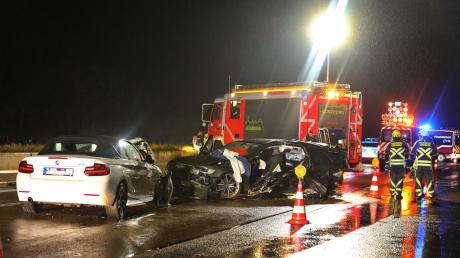 Feuerwehrleute stehen neben zwei Unfallwagen. Ein Autofahrer hat auf der A8 einen Unfall verursacht, in dessen Folge drei weitere Autos ebenfalls verunglückten. 