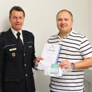 Ulms Polizeipräsident Bernhard Weber überreicht Andreas Bichert die Urkunde zur Bürgerehrung. 