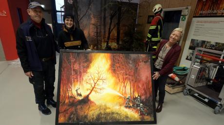 
Toni Baumann und die Künstlerin Lena Unverdorben übergaben das Bild "Waldbrand bei Fuchsenloch" in der Feuerwehrerlebniswelt an Ulrike Hartig (von links). 