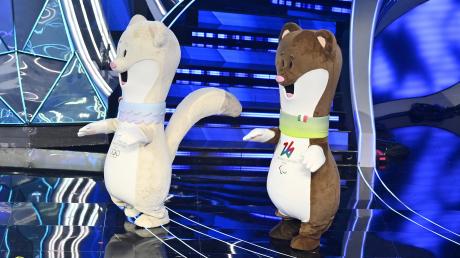 Tina und Milo, die beiden Maskottchen für die Olympischen Winterspiele 2026, stehen bei ihrer Präsentation auf der Bühne. 