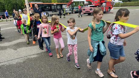 Der lange Feuerwehrschlauch muss von den Kindern gemeinsam getragen werden. Beim Besuch der Neuburger Feuerwehr lernt die Kinderfeuerwehr Zell wichtiges Equipement kennen.