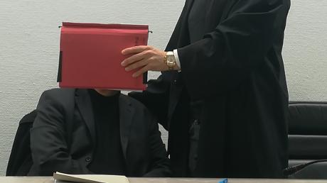 Ein Pfarrer stand in einem Berufungsverfahren vor dem Landgericht Ingolstadt. Der Vorwurf: sexueller Missbrauch. Auf dem Bild hält sein Anwalt ihm eine Mappe vors Gesicht - kurz vor der Urteilsverkündung.