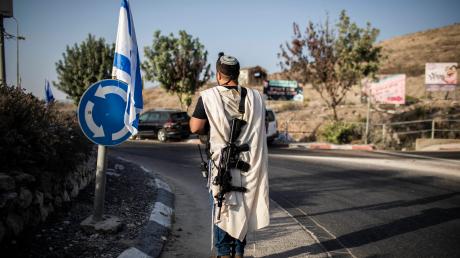 Ein bewaffneter israelischer Siedler steht nahe der palästinensischen Stadt Nablus im nördlichen Westjordanland.