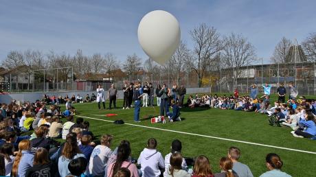 Schülerinnen und Schüler der P-Seminare Physik und Chemie lassen Sportplatz des DZG in Landsberg einen Stratosphärenballon steigen. Die halbe Schule schaut dabei zu.