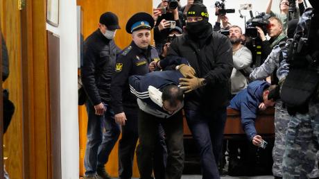 Ein Tatverdächtiger des Terroranschlags auf die Konzerthalle "Crocus City Hall" wird von Sicherheitskräften zur Vorführung in einen Moskauer Gerichtssaal gebracht. 