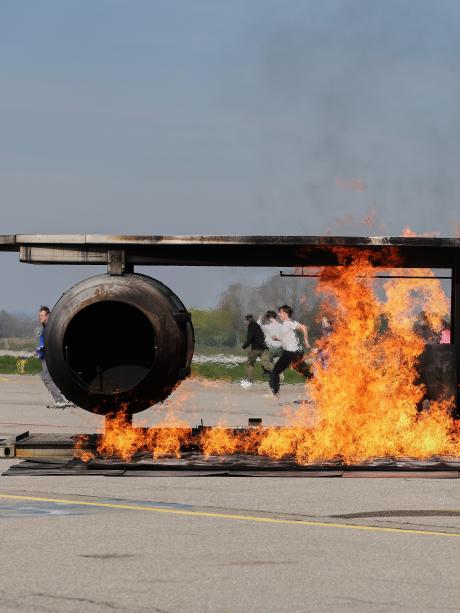 Der Flugzeugsimulator brennt. Im Hintergrund bringen sich die Passagiere in Sicherheit.