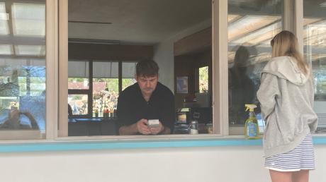 Peter Kaun junior ist der neue Pächter des Strandbads St. Alban. Das Foto zeigt ihn beim Programmieren der Kasse, während eine Mitarbeiterin die Fensterscheiben am Kiosk zum Glänzen bringt.