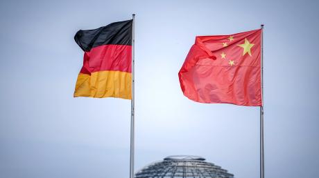 Die Flaggen von Deutschland und China wehen vor der Kuppel des Reichstagsgebäudes.