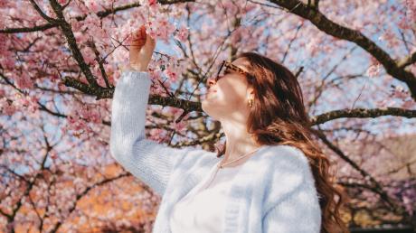 Christina Kling posiert vor einem blühenden Kirschbaum.