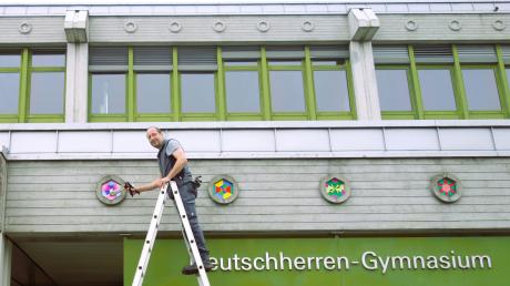 Hausmeister Jochen Hoffmann befestigte die lackierten Schichtleimplatten in den Aussparungen der Sichtbetonfassade am Aichacher Deutschherren-Gymnasium.