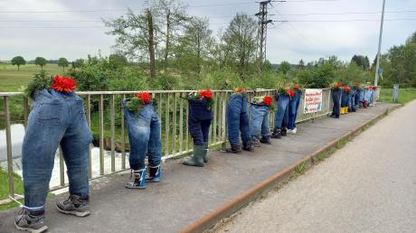 Mehrere ausgestopfte Puppen stehen in Fleinhausen auf der Brücke über der Zusam. 
