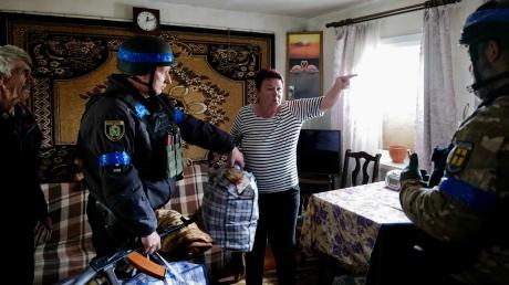 Tetjana und ihr Mann müssen ihr Haus verlassen. Es ist höchste Zeit, in der Nähe brennen Häuser. Polizist Vitali (Zweiter von links) hilft ihnen.
