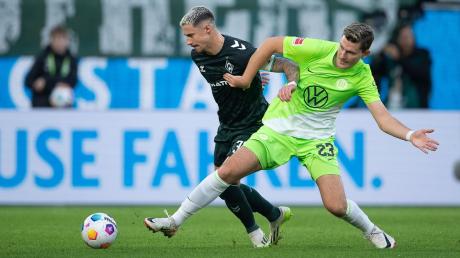 Wolfsburgs Jonas Wind (r) im Zweikampf mit dem Bremer Marco Friedl.