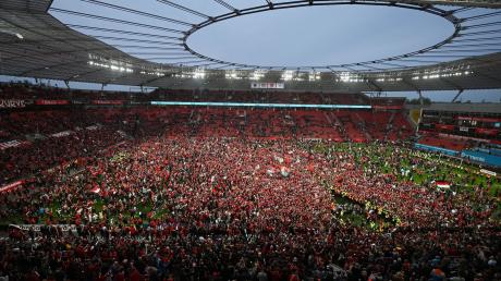 Leverkusens Fans bejubeln auf dem Rasen den Gewinn der Deutschen Meisterschaft.