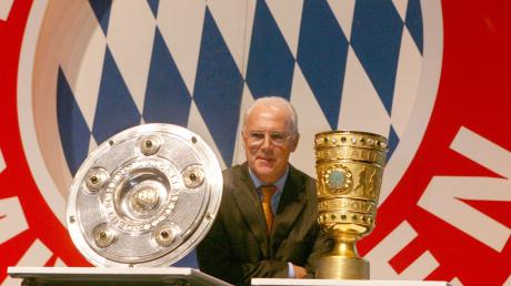 Franz Beckenbauer 2006 zwischen Meisterschale und DFB-Pokal.