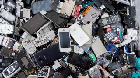 Alte Handys und Smartphones liegen in einem Container, ehe sie geschreddert werden. Davor sollten wertvolle Metalle und seltene Erden noch recycelt werden.