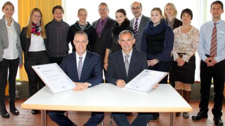 Jochen Kläger (links) und Schulleiter Markus Reutter unterzeichneten im Beisein von Schülern die Vertragsurkunde für die Schulpartnerschaft.  

