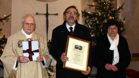 Monsignore Josef Philipp und Pfarrgemeinderatsvorsitzende Herta Zacher ehrten den langjährigen Kirchenpfleger Emil Reck (Mitte).  
