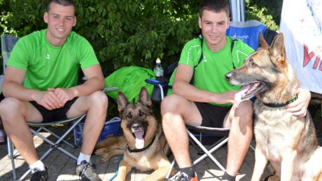 Denis (links) und Gerrit Lux (rechts) sitzen mit ihren Schäferhunden Quinto und Ricko entspannt im Schatten und schauen sich die anderen Wettkämpfe an. 