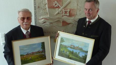Rudolf Grabmair (links) übergab Bürgermeister Gerhard Pfitzmaier zwei von ihm gemalte Ansichten von Donauwörth und Neuburg. 
