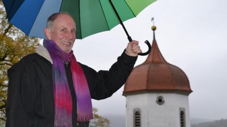 Weiß sich nicht nur bei Regen gut geschützt: Der neue evangelische Stadtpfarrer Udo Molinari vor dem Hintergrund der Kirche St. Barbara. 
