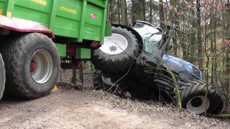 Dieser Traktor samt Miststreuer-Anhänger ist in einem Wald gelandet.