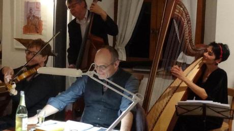 Dirk Heißerer (lesend am Tisch) und ein  Teil der  Gempfinger Hofmarkmusik (dahinter) zogen einmal mehr ihr Publikum im Gempfinger Pfarrhof in ihren Bann. 