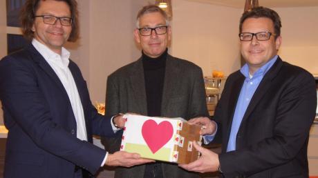 Die beiden Weka-Geschäftsführer Stephan Behrens (links) und Michael Bruns (rechts) überreichen Andreas Schmidt von der Friedberger Allgemeinen eine gut gefüllte Spendenbox für die Kartei der Not. 