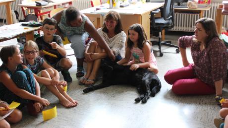 An der Grundschule Waldstetten findet seit Kurzem Unterricht mit Hundetrainerin Silke Katzer (Mitte) und Schulhund Fee statt. Bei dieser Szene bespricht Rektorin Julia Lerch (rechts) die Ergebnisse einer Projektarbeit im Sitzkreis. 